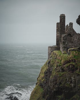 Moody view of Dunluce Castle perched on rugged cliffs above the sea in Northern Ireland.