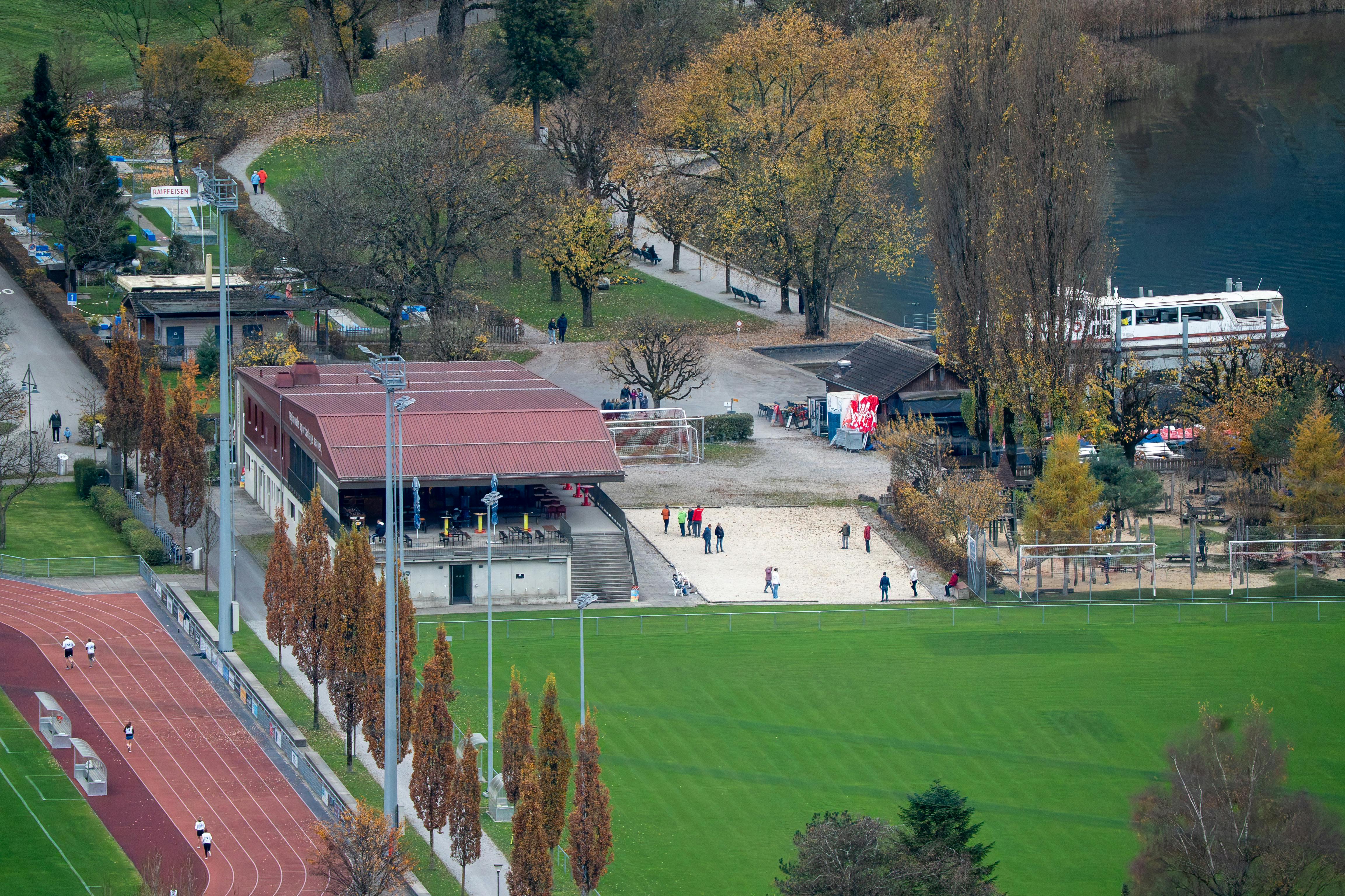 A scenic aerial view of sports fields near a lake in Sarnen, Switzerland during autumn.