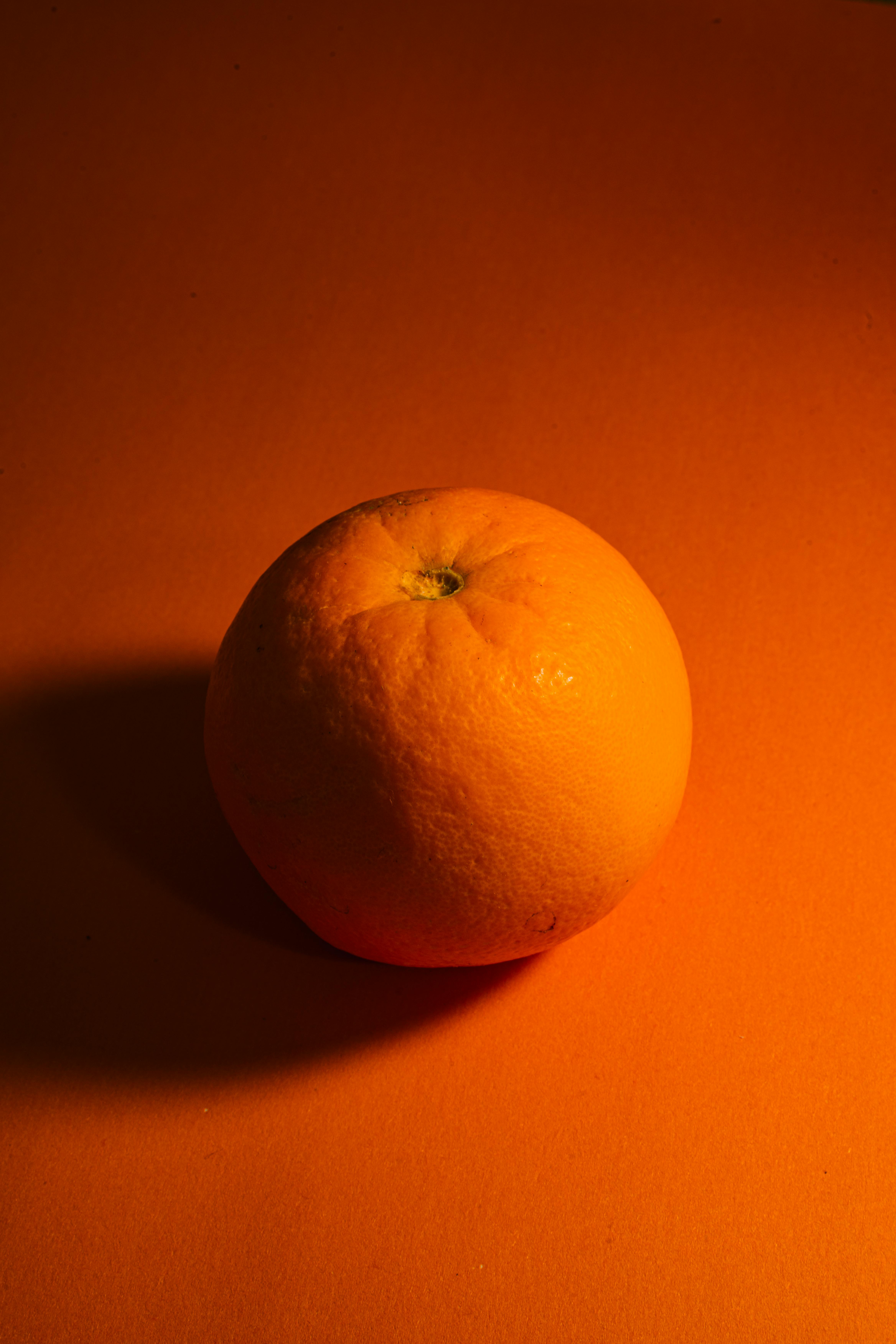 Gratis Minimalistisk bilde av moden appelsin på oransje bakgrunn med studiobelysning. Arkivbilde