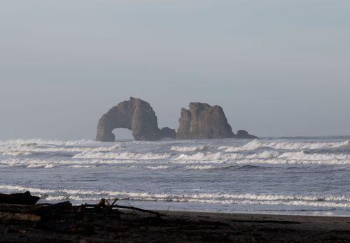 Free Waves crash against dramatic coastal rock arches under a serene sky. Stock Photo
