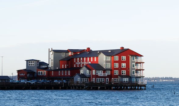 Red and grey waterfront hotel set against a serene ocean view during daylight.