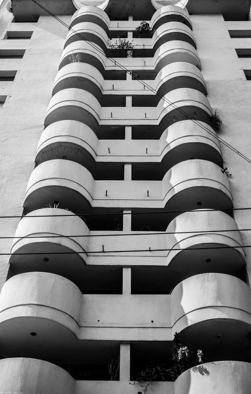 Free Monochrome view of a high-rise building with curved balconies from below. Stock Photo