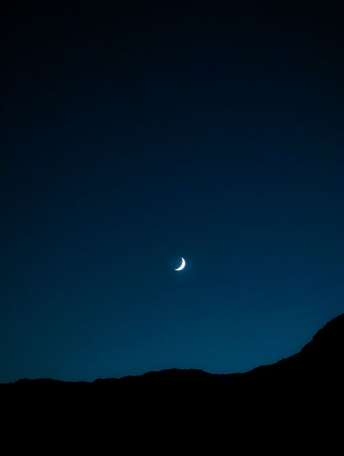 Free A serene crescent moon against a deep blue night sky in Dahab, Egypt, capturing tranquility and the beauty of nature. Stock Photo