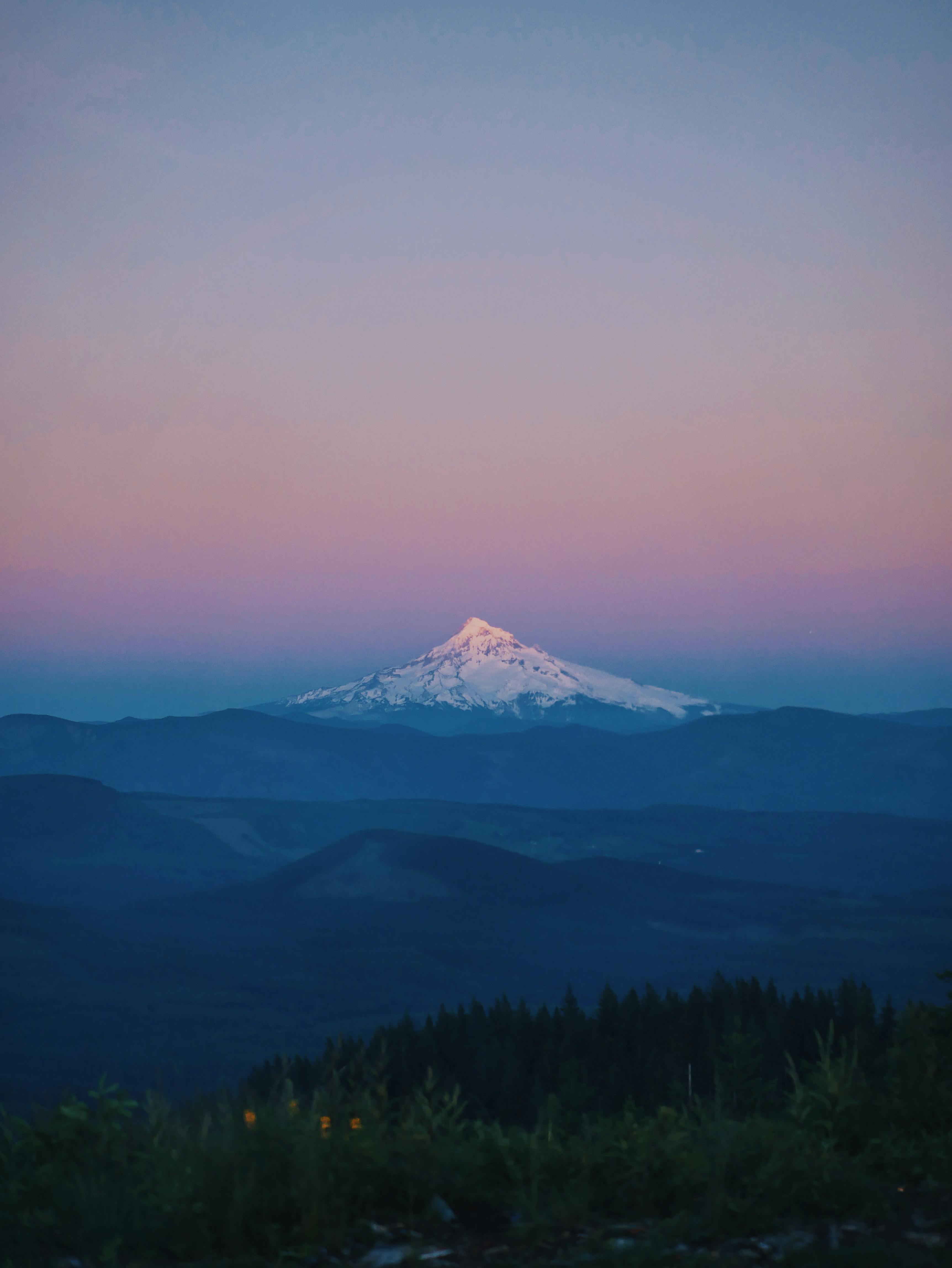 白雪皑皑的雄伟山下，美丽的日落映照着天空，构成一幅完美的旅行与自然画卷