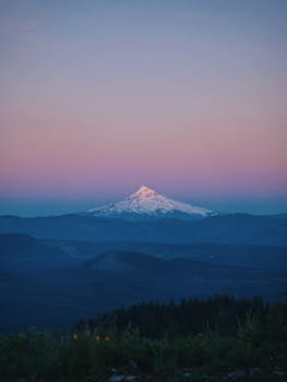 Majestic snow-capped mountain under a pastel sunset sky, perfect for travel and nature themes.