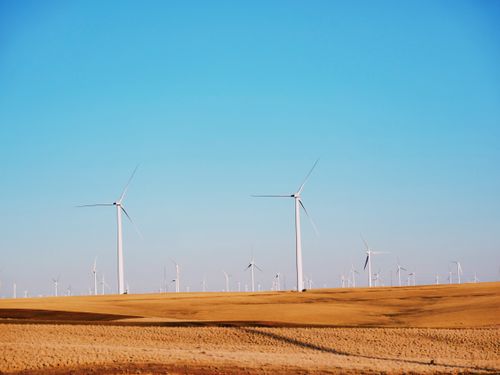 Free High wind power plant generating electricity located on flat desert sandy area against cloudless blue sky Stock Photo