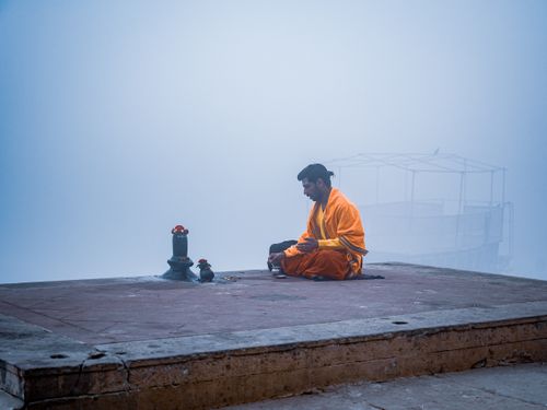 Free A Hindu monk meditates in solitude on a misty morning by the Ganges River in Varanasi, India. Stock Photo