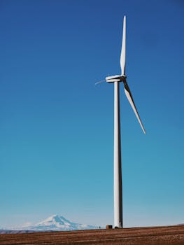 Photo by Aleksey Kuprikov A wind turbine in a rural landscape under a vibrant blue sky, symbolizing renewable energy.