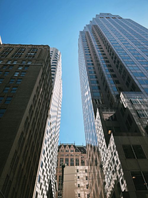 Free Looking up at modern skyscrapers in a vibrant city under a clear blue sky. Stock Photo
