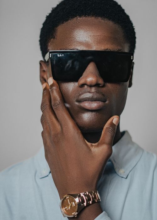 Free Portrait of a fashionable young man with sunglasses and a watch, posing confidently. Stock Photo