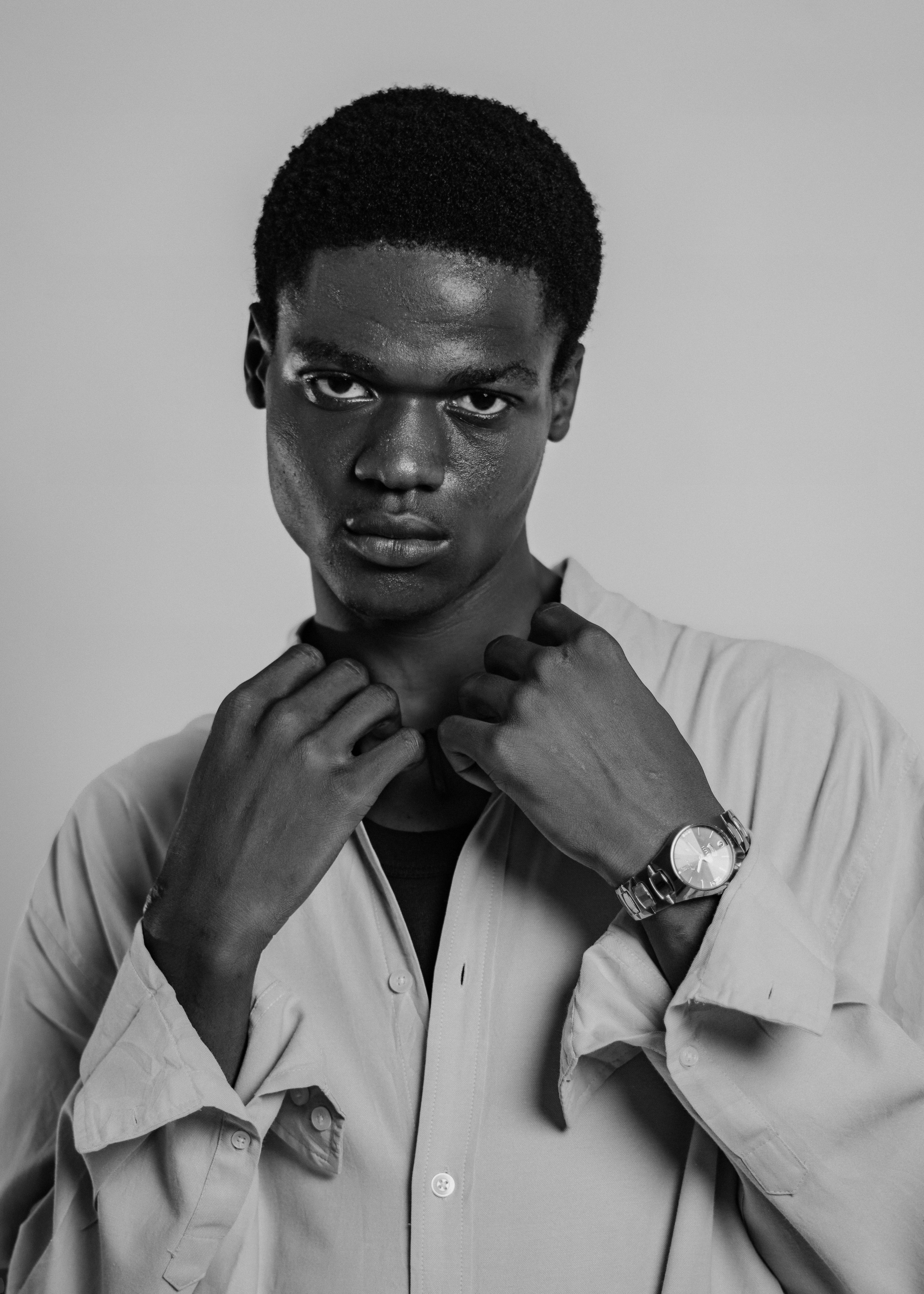 Moody black and white portrait of a young man posing in a shirt.