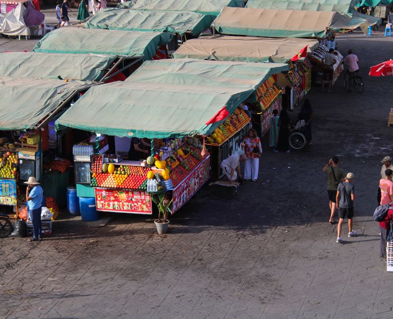 Busy Moroccan market scene with colorful textiles and local vendors.