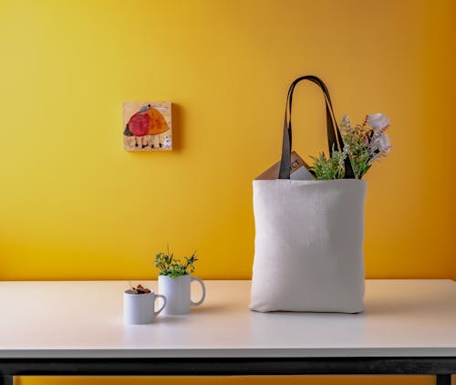 Two White Ceramic Mugs and a white bag on Wooden Table