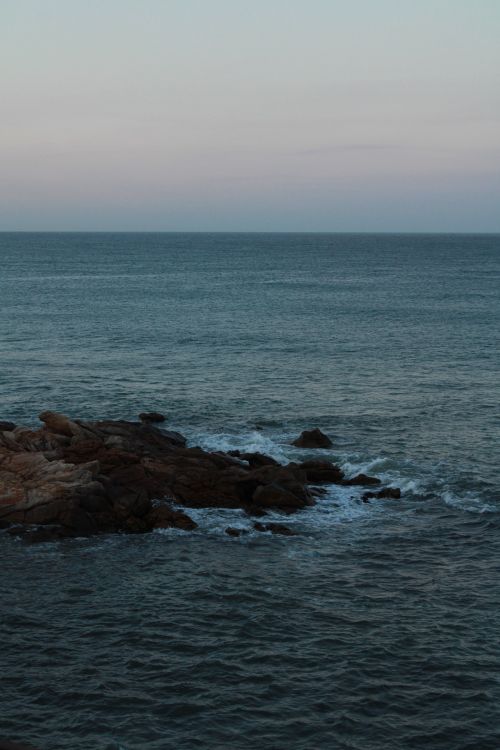 Free Peaceful coastal scene with rocky shoreline in Morocco during twilight hour. Stock Photo