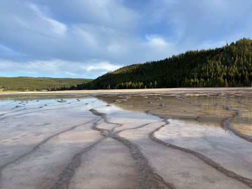 Free Scenic view of Grand Prismatic Spring's terraces under a partly cloudy sky, showcasing vivid natural patterns. Stock Photo