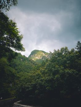 A scenic view of a lush, green mountain under a dramatic, cloudy sky. Ideal for nature and travel themes.