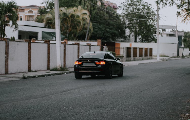 Car Driving Along Empty Street In Suburb