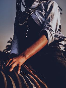 Close-up of a woman riding a horse, emphasizing fashion and elegance at sunset.