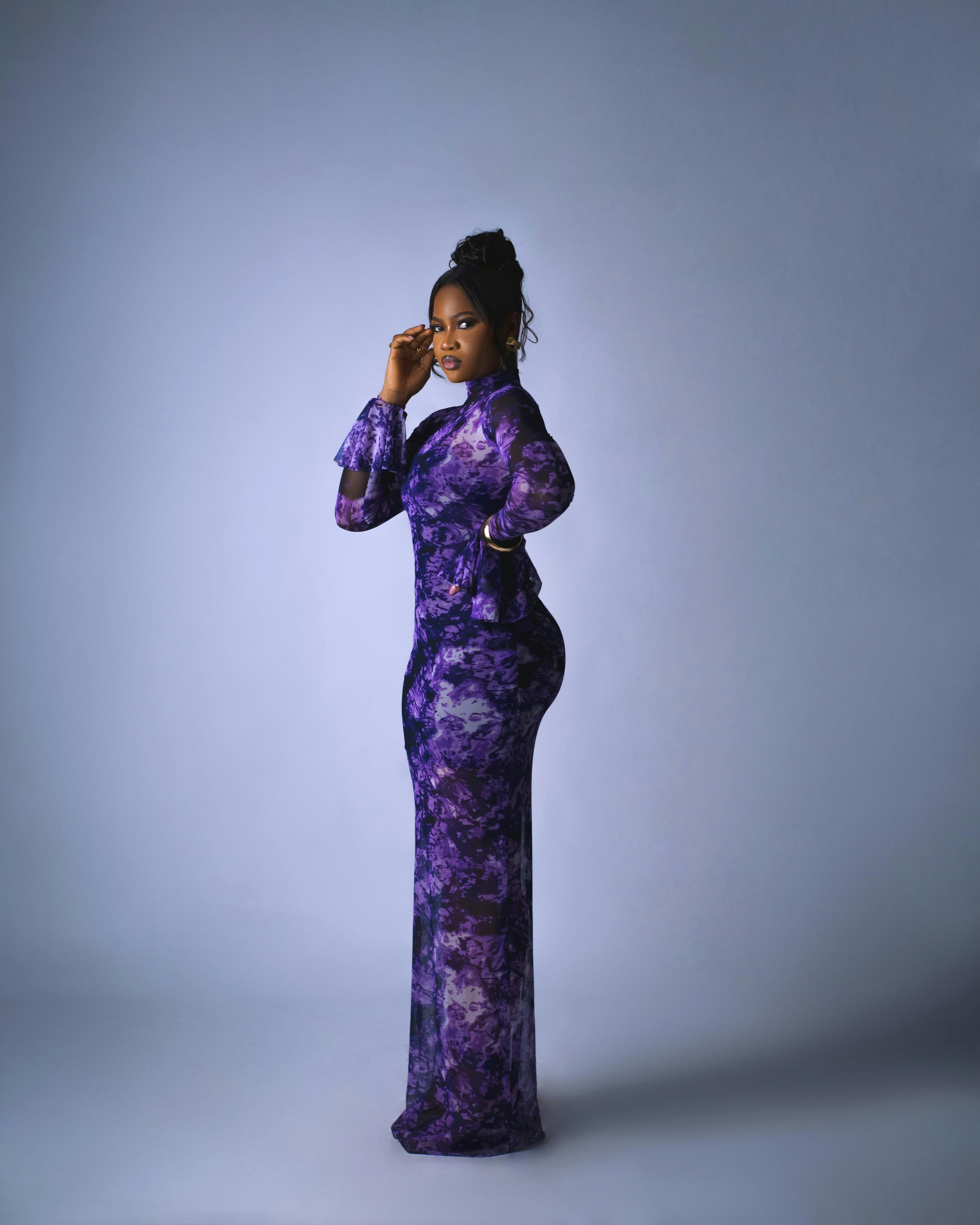 grátis Um impressionante retrato de estúdio de uma mulher com um vibrante vestido roxo contra um fundo neutro. Foto profissional