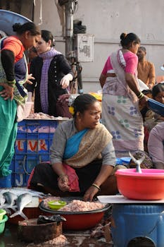 A vibrant fish market in India with women selling seafood and engaging in lively trading.