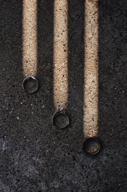 Three wedding rings casting dramatic shadows on textured surface.