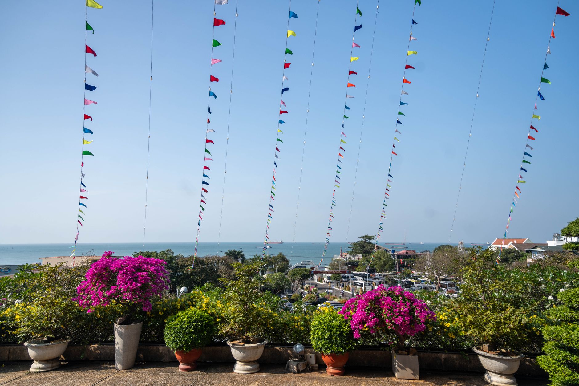Vibrant flags and blooming flowers overlooking the waterfront in Vũng Tàu, Vietnam.