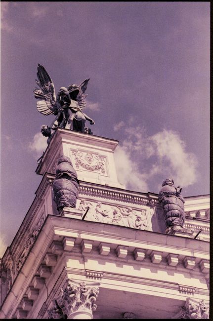Dramatic view of an angel statue atop the Lviv Opera House, Ukraine under a vibrant sky.