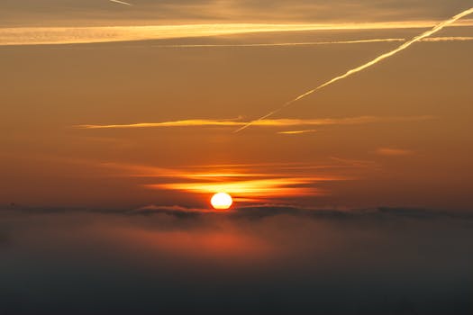 Captivating sunrise scene with vibrant orange hues over a misty cloud-covered landscape.