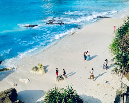 A beautiful aerial view of a tropical beach in Bali with people enjoying the sun.
