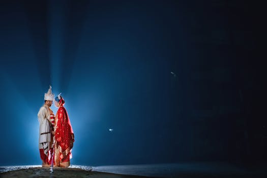 A couple in traditional Indian attire during a wedding ceremony under dramatic lighting at night.