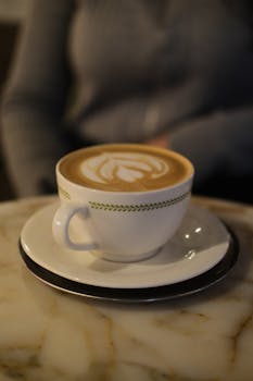 Close-up of a latte with beautiful art on a marble table, creating a cozy coffee shop vibe.