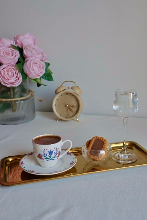 Free A sophisticated tea setting with a cup, roses, and an antique clock. Stock Photo