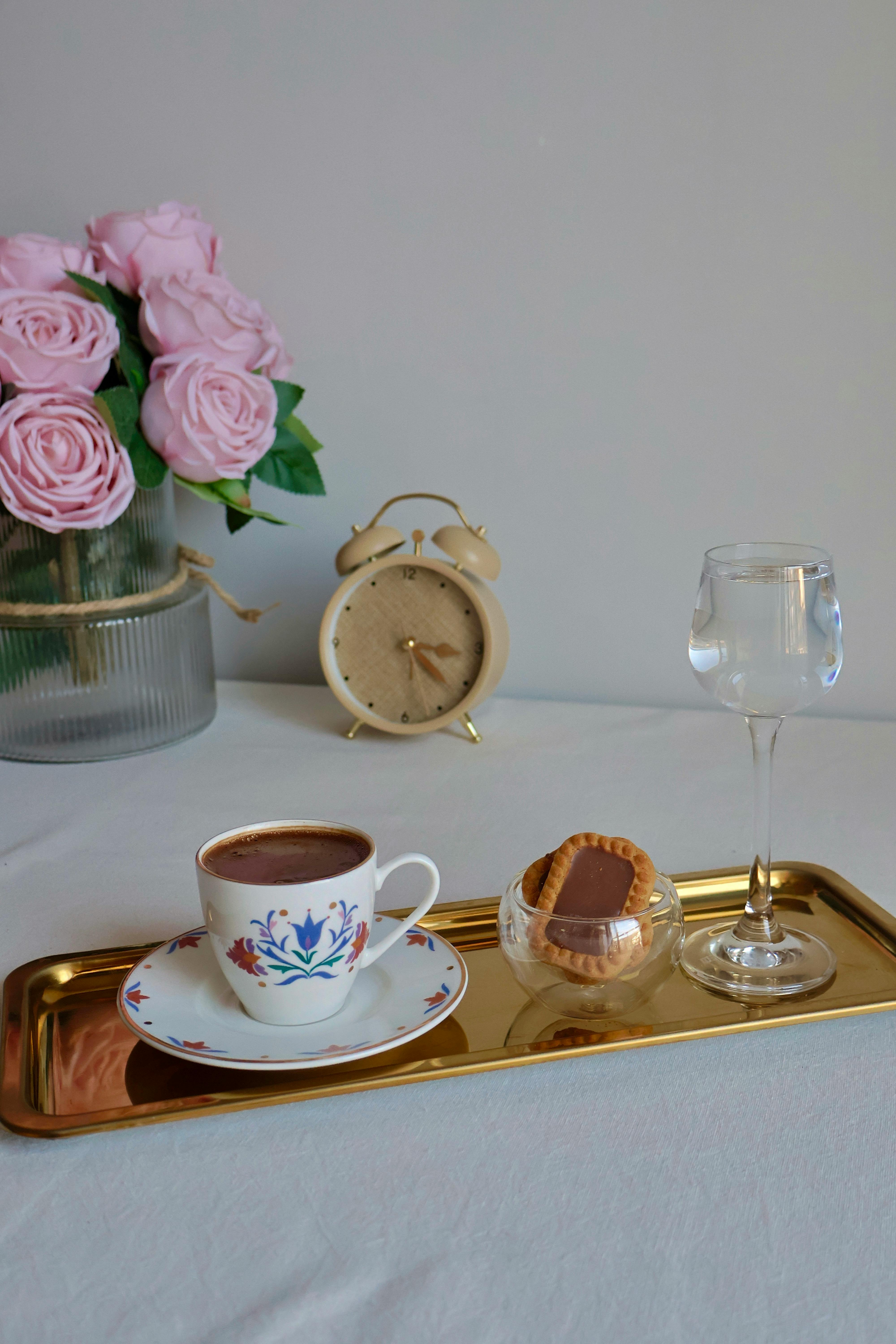 grátis Um sofisticado conjunto para chá com xícara, rosas e um relógio antigo. Foto profissional