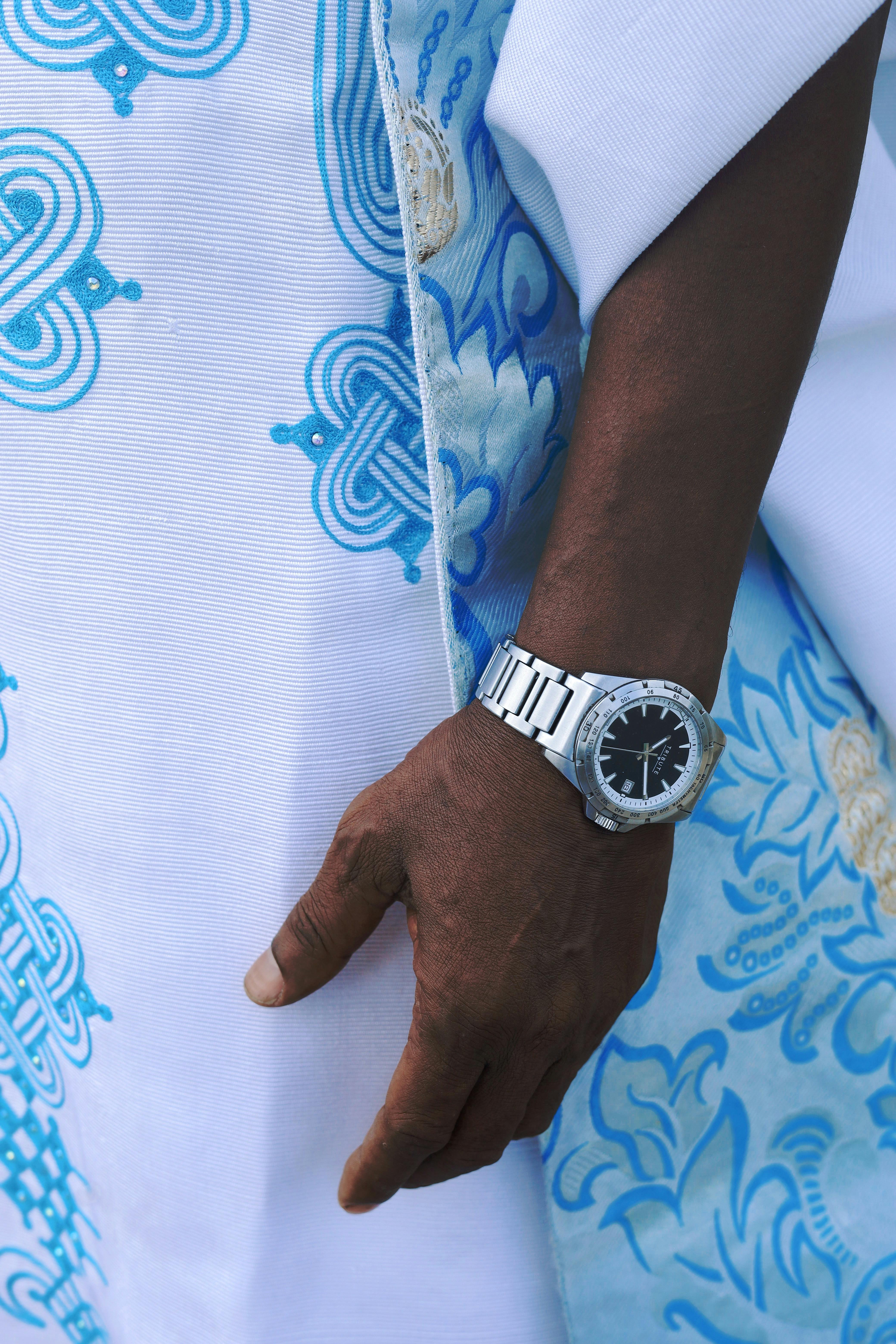 De franc Estil sofisticat amb un rellotge platejat i un primer pla de teixit blau ornamentat. Foto d'estoc