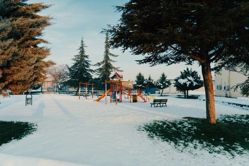 Free A serene playground covered in snow during winter, framed by trees under a clear sky. Stock Photo