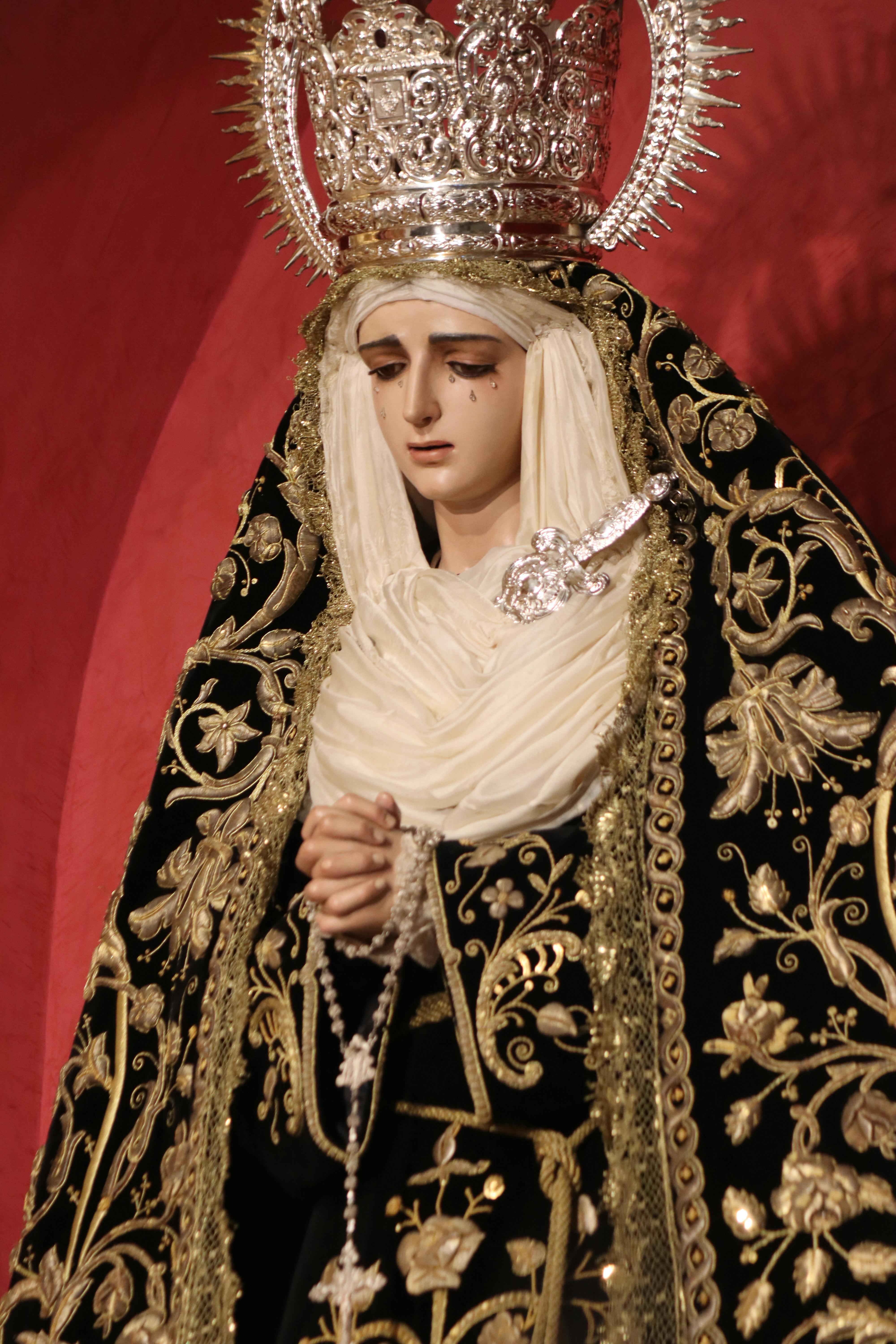 Intricate statue of a weeping Madonna in ornate attire, holding a rosary.
