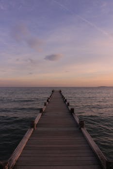 Serene sunset view from a wooden dock over calm waters, perfect for relaxation.