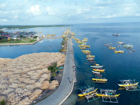 Aerial view of vibrant fishing boats in Bolinao harbor, a serene coastal scene in the Philippines.