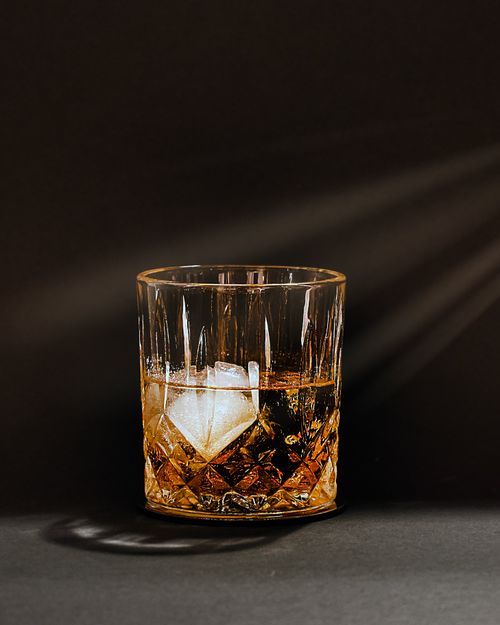 Free A classic crystal glass of whiskey on the rocks against a dark background, exuding elegance and sophistication. Stock Photo