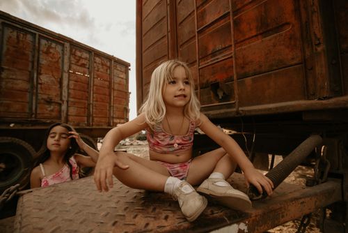 Free Two children in colorful outfits playing on an old train car in a sunny outdoor setting. Stock Photo