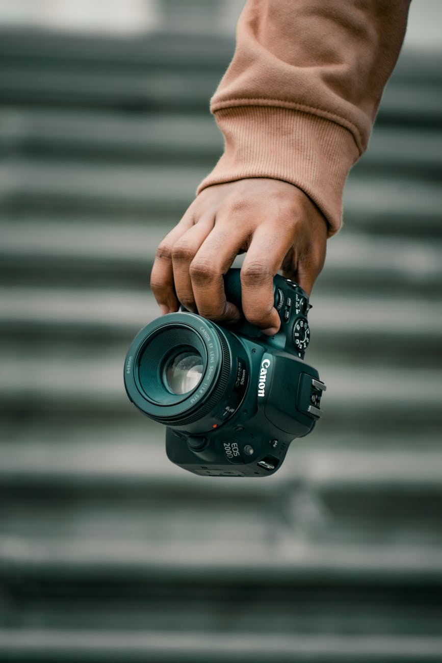 A close-up of a hand confidently holding a DSLR camera, showcasing photography essentials outdoors.