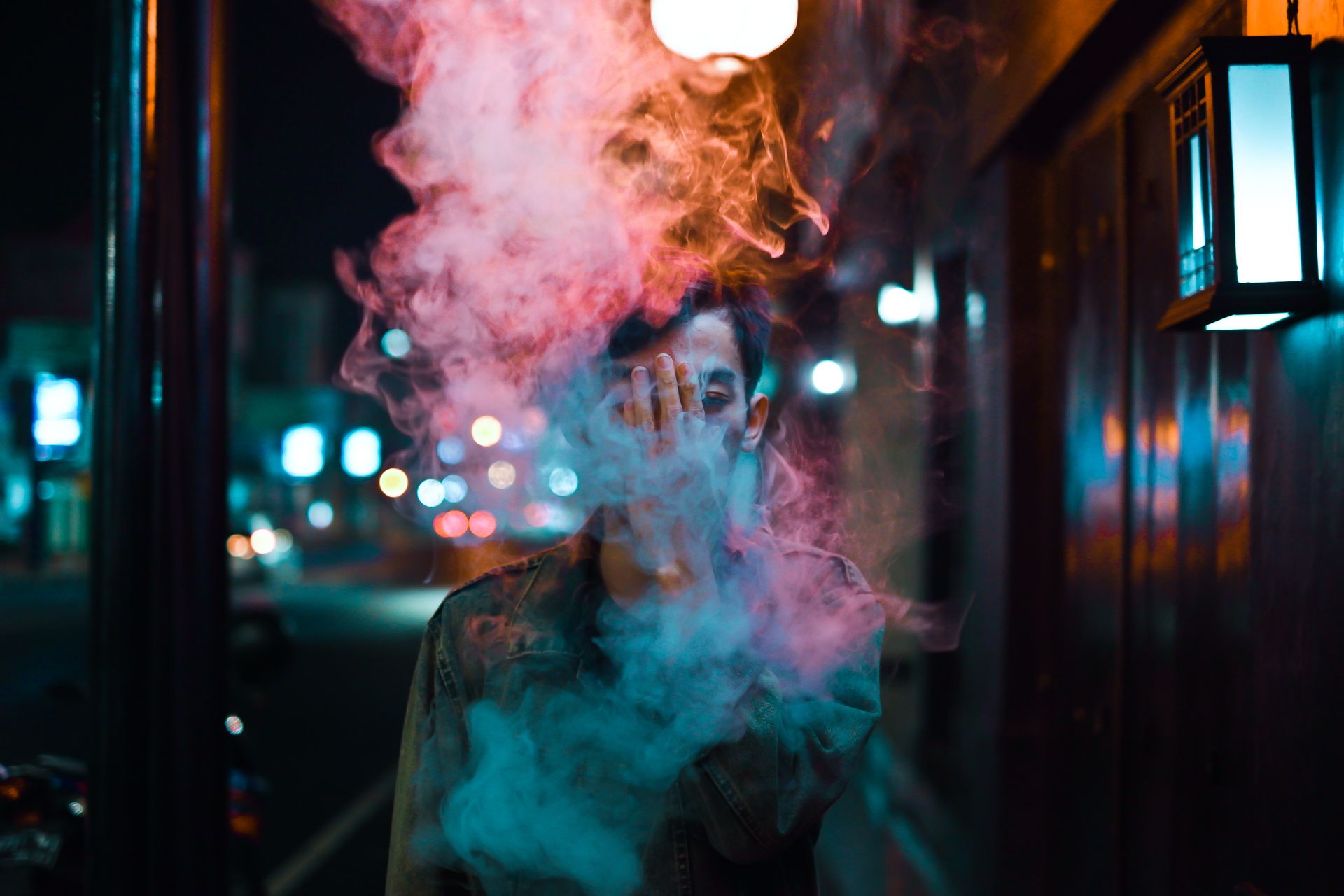 Mysterious street portrait of man obscured by smoke, creating moody urban atmosphere.