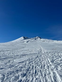 Expansive snowy mountain under a vibrant blue sky, serene winter scene.