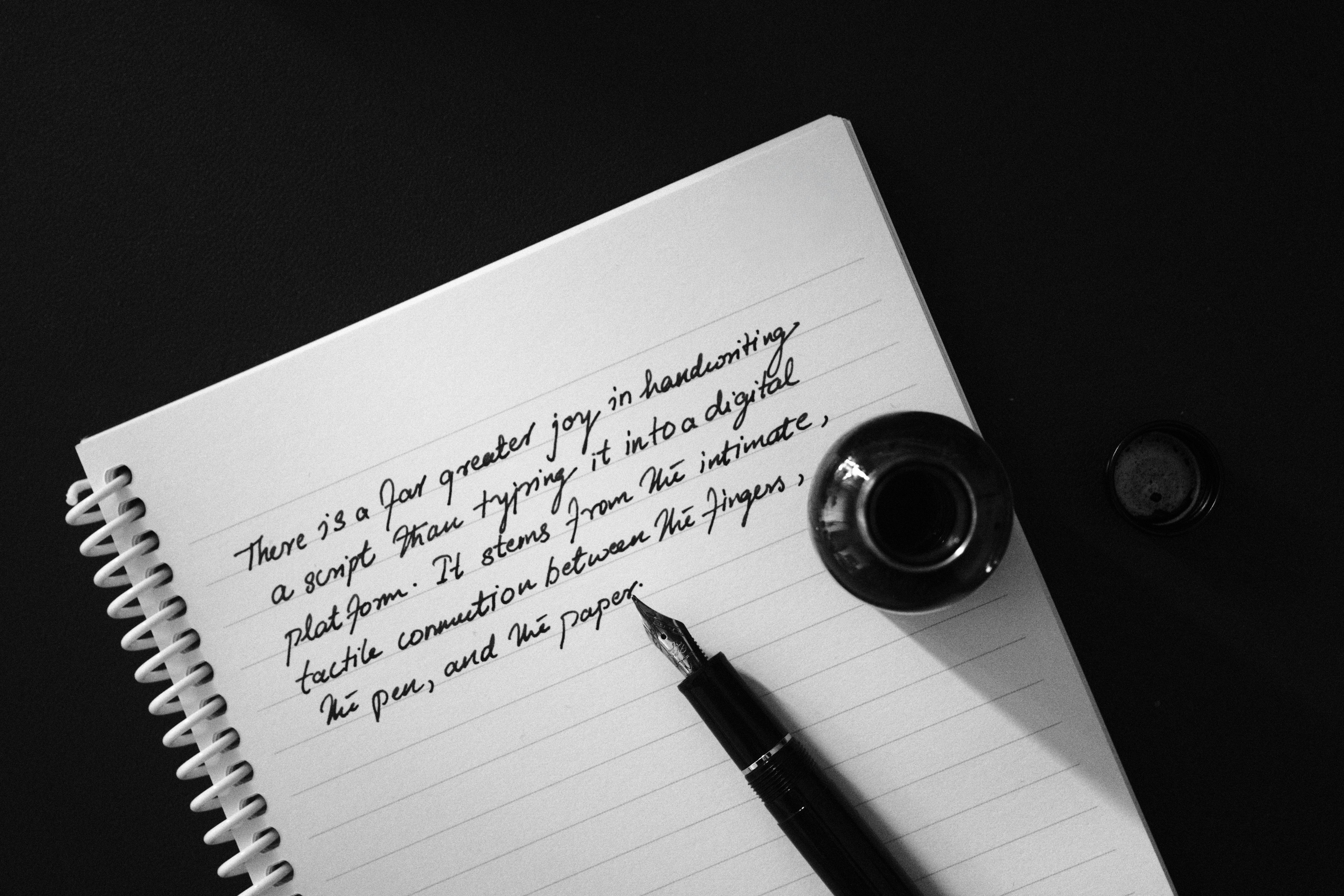 Gratis Immagine in bianco e nero di un testo scritto a mano con una penna stilografica e una boccetta d'inchiostro su un quaderno. Foto a disposizione