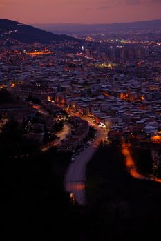 Dusk cityscape view with warm lights illuminating a bustling urban area.