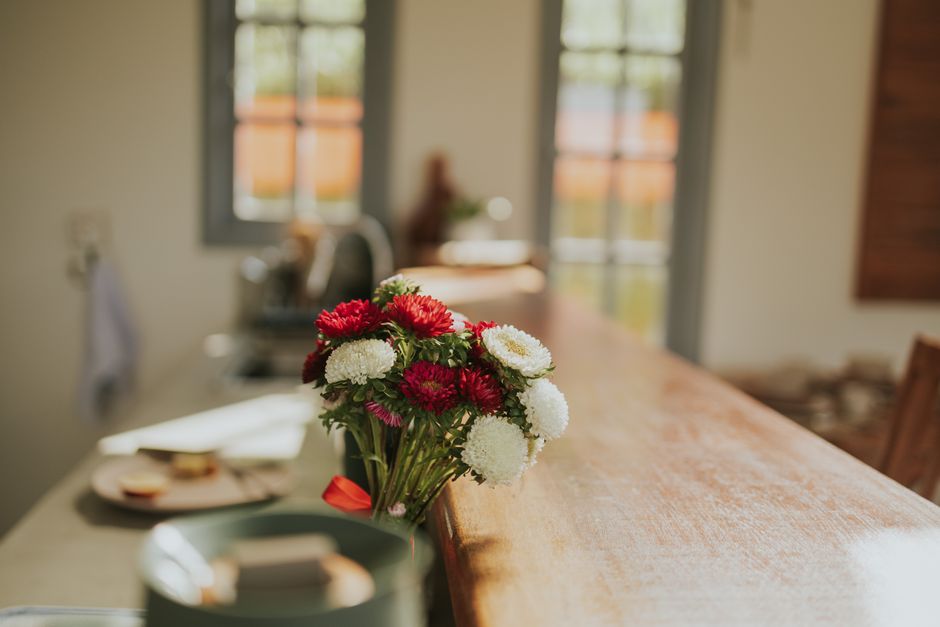 A vibrant bouquet of red and white flowers on a wooden counter in a sunny room.