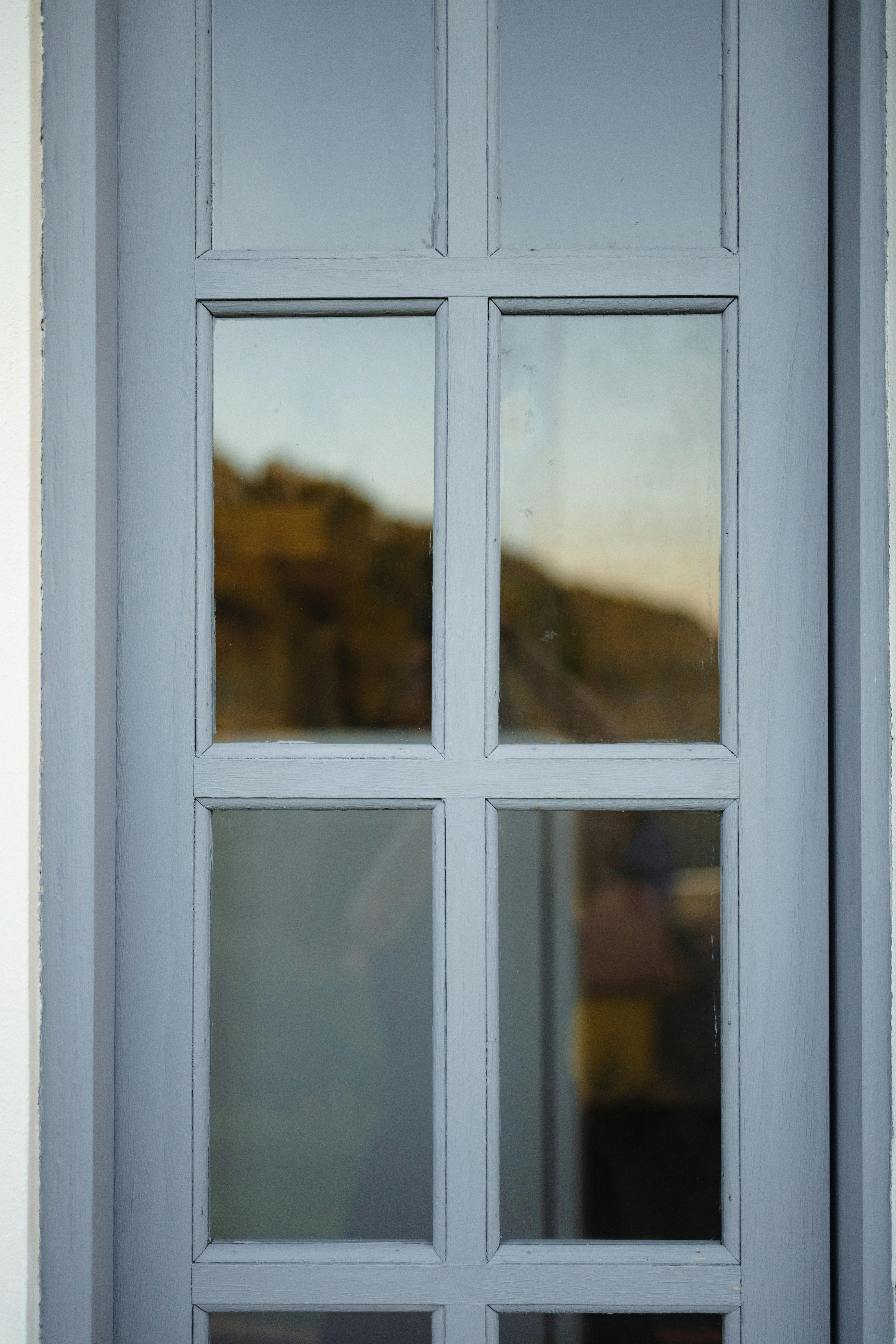 Kostenlos Ein minimalistisches graues Fenster reflektiert den Blick nach draußen mit verschwommener Landschaft. Stock-Foto