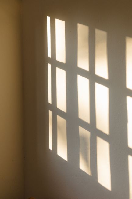 Minimalist image of window shadows projected on a wall, creating a geometric pattern.