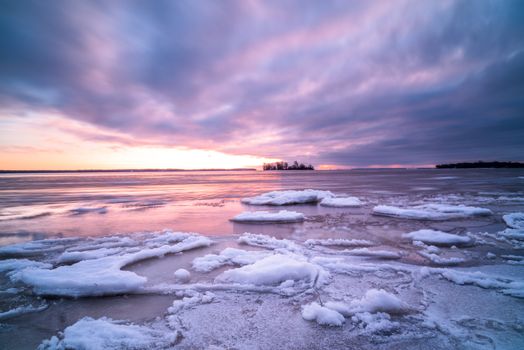 A tranquil winter scene of icy waters and a vibrant sunset in Montreal, Quebec, Canada.