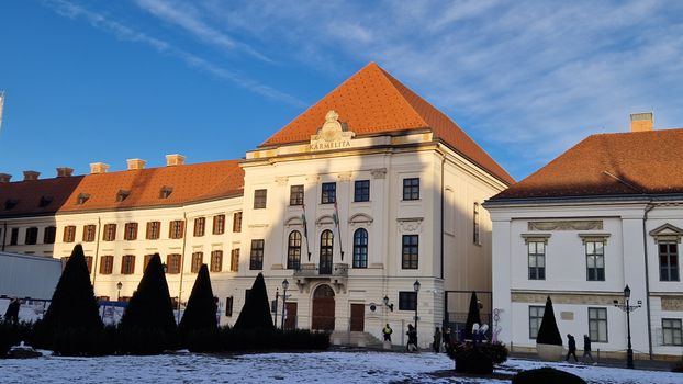 Karmelita building with red roof in winter sunlight, clear blue sky in the background.